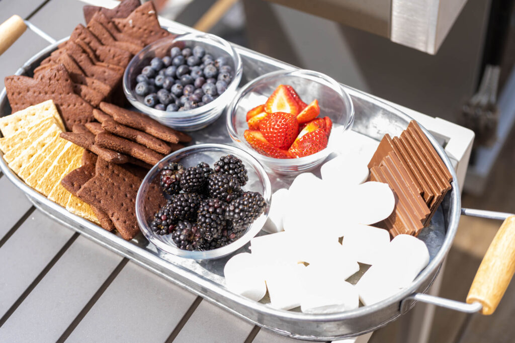 chocolate, graham crackers, fruit and marshmallows in a silver tray