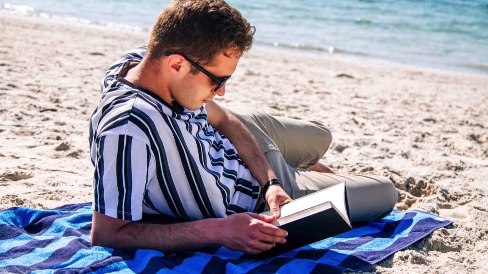 Man in beach reading book